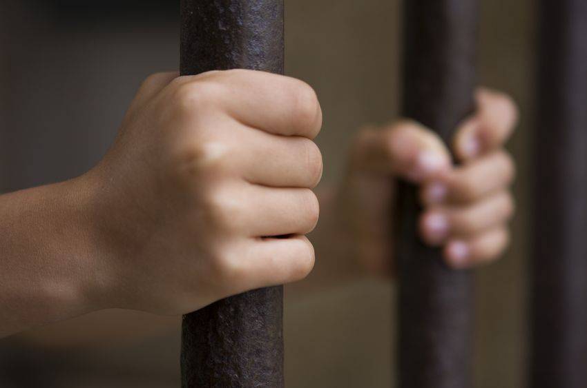 hands holding prison bars