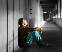 Child in institution sitting on floor with back to wall.