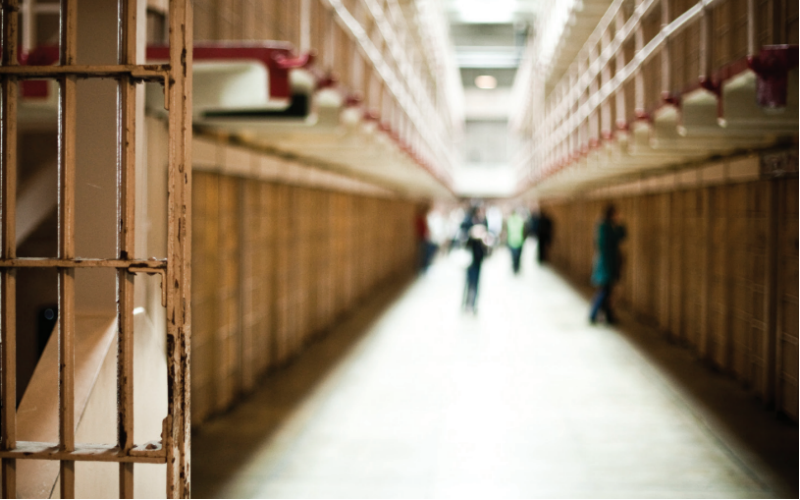 The interior of a jail. A jail cell door swinging open.
