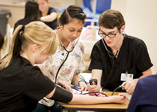 Three CNA students gathered around a table, studying