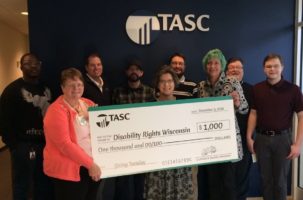 Theresa Zenchenko (left) and some members of her team hold an oversized check for Lea Kitz, DRW’s Executive Director (middle).